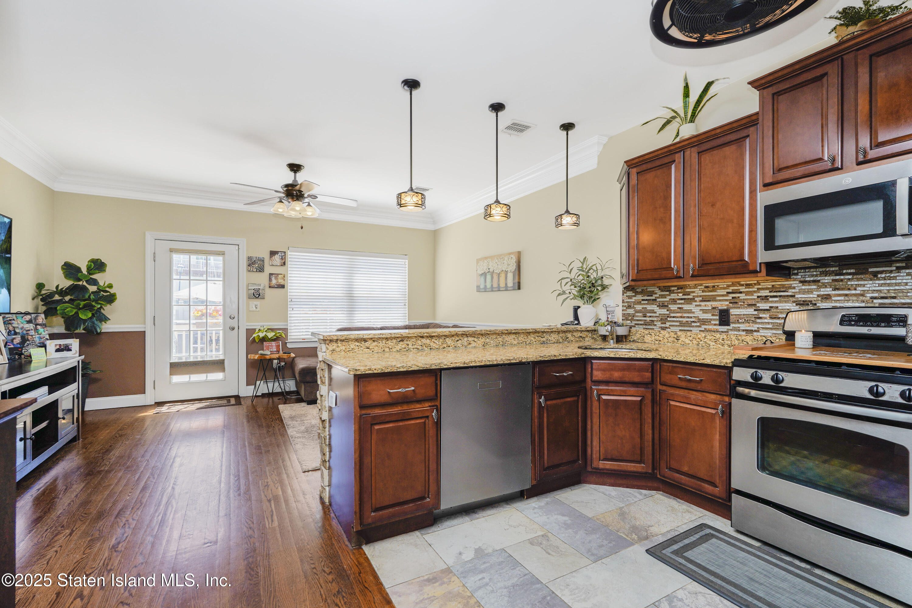 84 Presentation Circle Staten Island, NY 10312 - Photo 13 of 35 a kitchen with stainless steel appliances granite countertop a stove a sink dishwasher and a microwave oven with wooden floor