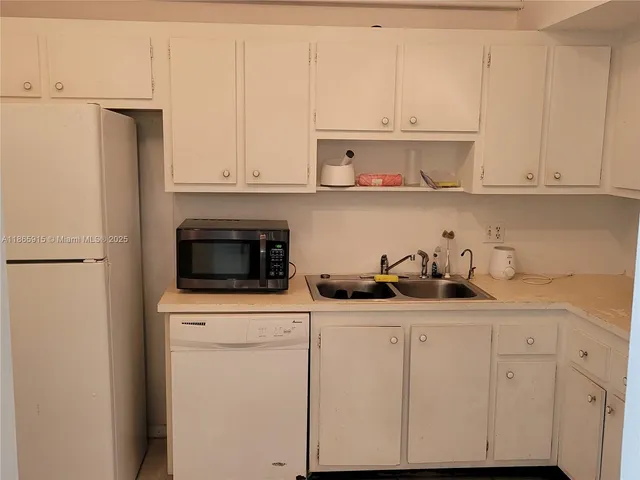 a kitchen with white cabinets and appliances