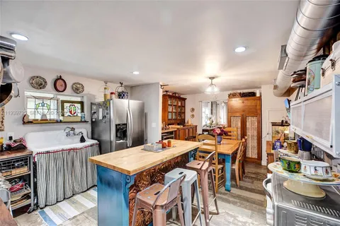 a open kitchen with stainless steel appliances kitchen island granite countertop a table chairs and a refrigerator