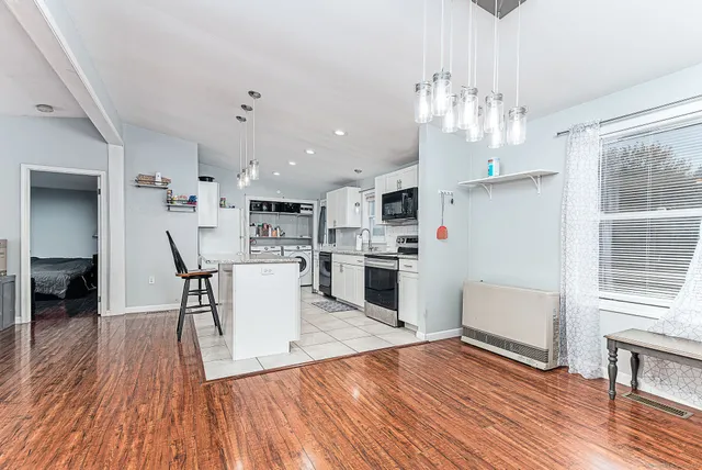 a kitchen with granite countertop a refrigerator a stove top oven and cabinets with wooden floor