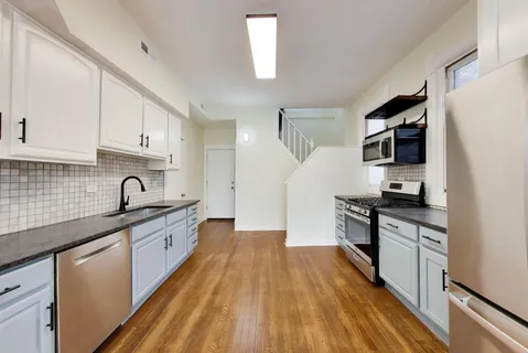 a kitchen with granite countertop a sink wooden floor and stainless steel appliances