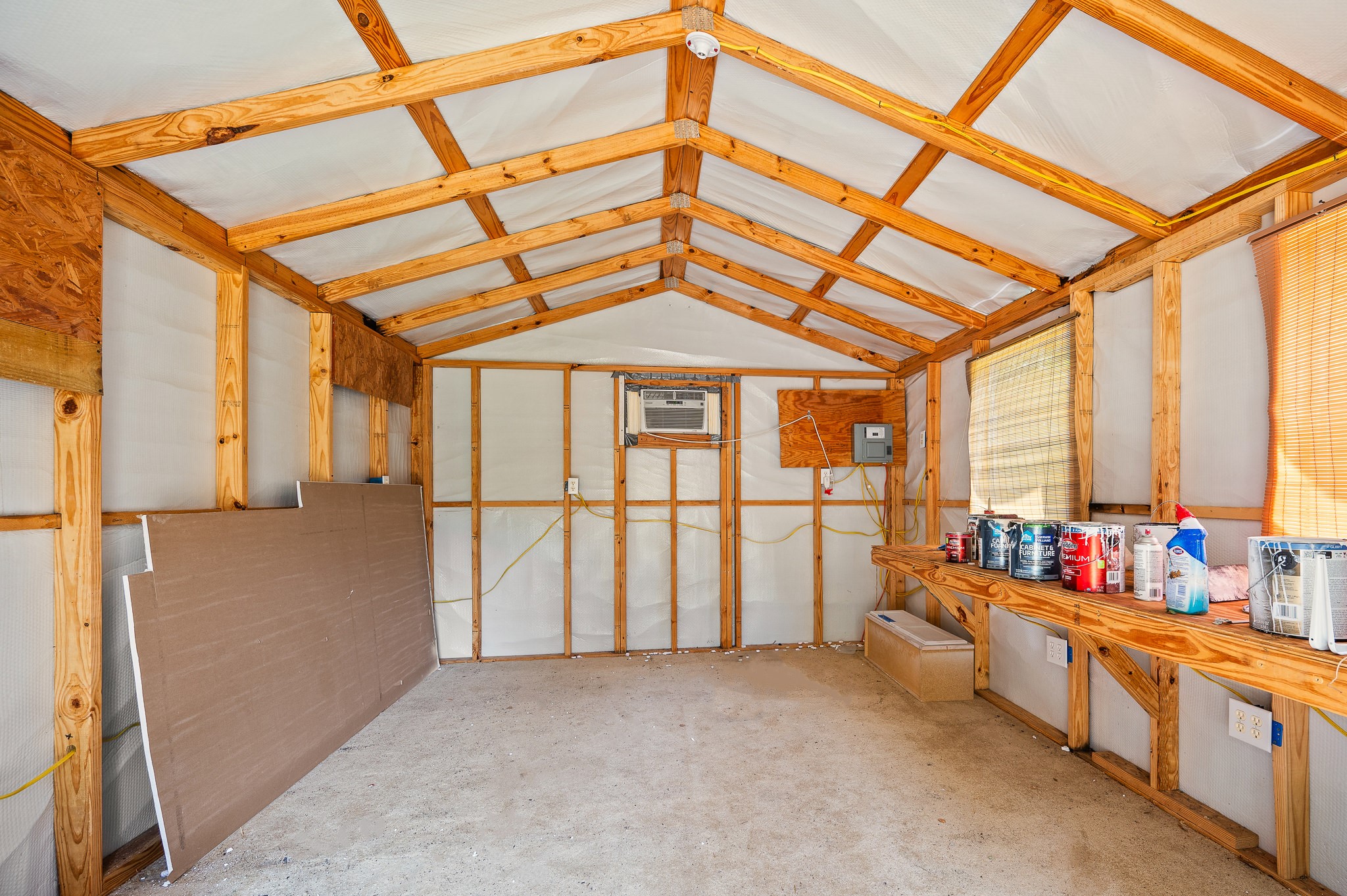 61 Hicks Loop West Cleveland, TX 77328 - Photo 32 of 38 Spacious workshop with exposed wood framing, perfect for projects or storage, featuring an air conditioning unit for comfort.