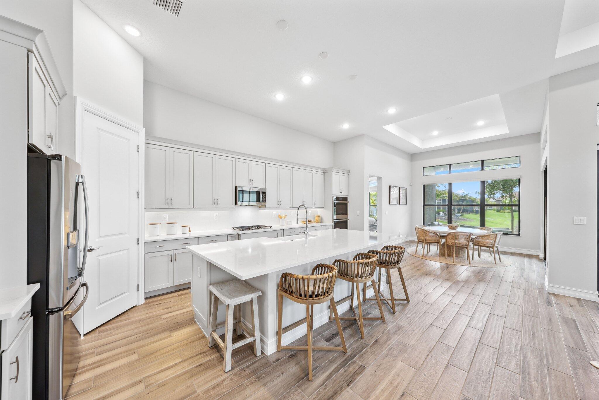 11786 Vivar Run Parkland, FL 33076 - Photo 6 of 46 a kitchen with a table chairs refrigerator and cabinets