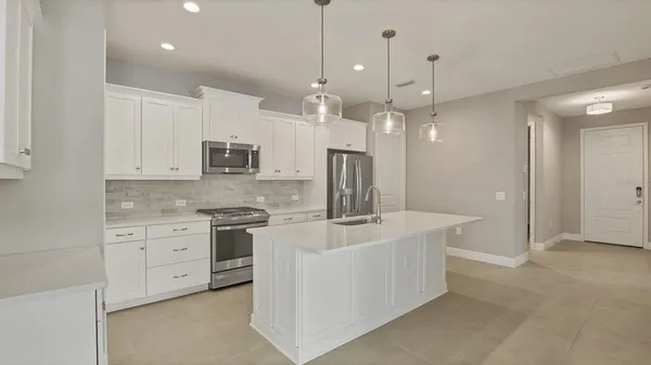 a kitchen with stainless steel appliances granite countertop a refrigerator a sink a stove a dining table and chairs with wooden floor