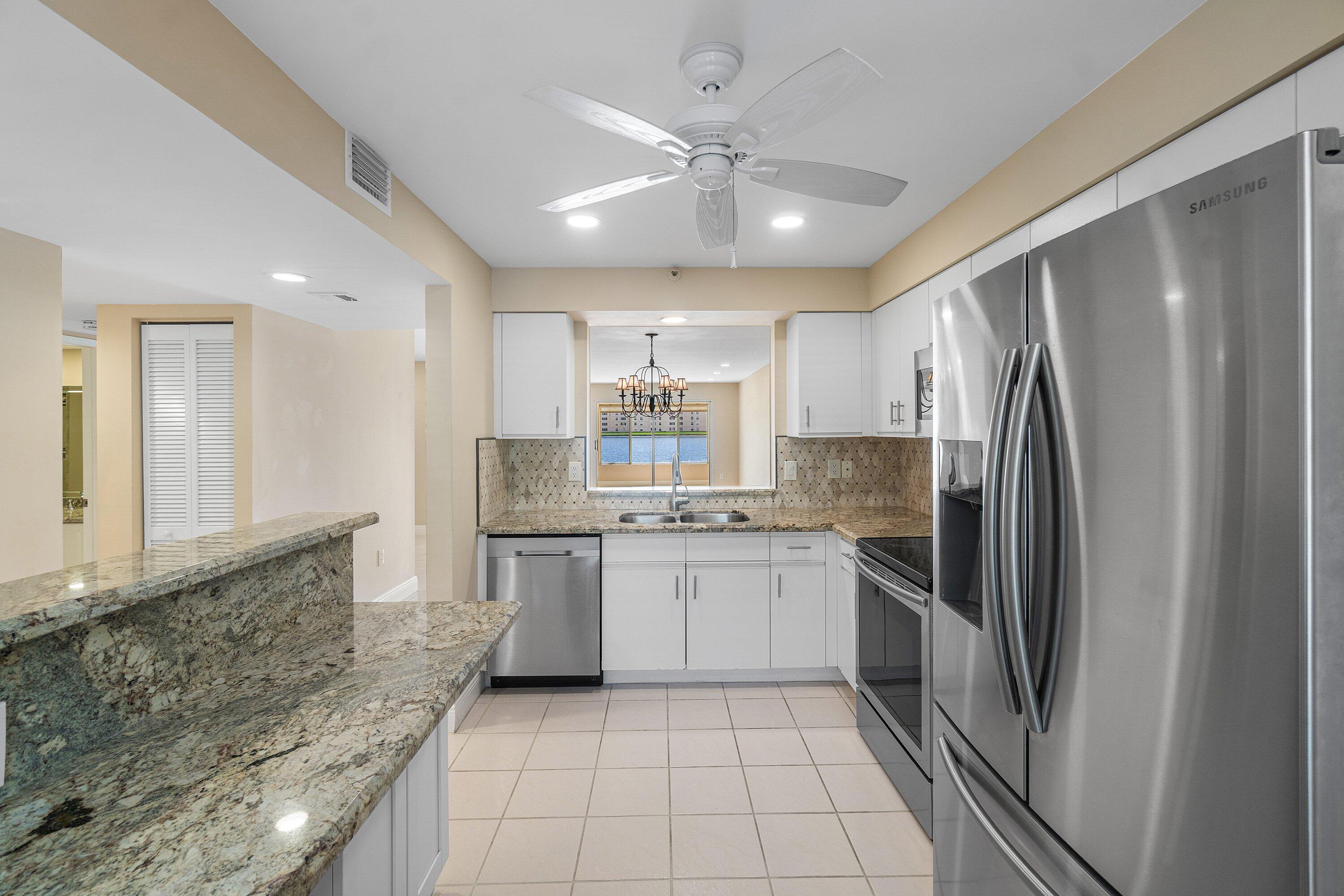 14096 Huntington Pointe Drive, Unit 106 Delray Beach, FL 33484 - Photo 22 of 47 a kitchen with stainless steel appliances granite countertop a refrigerator and a sink