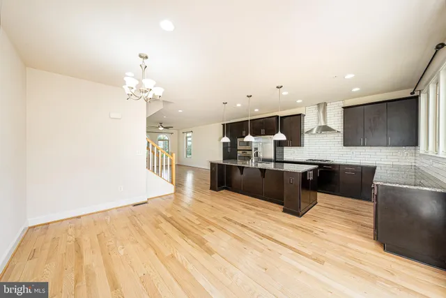 a kitchen with stainless steel appliances kitchen island granite countertop a refrigerator a sink and wooden floor