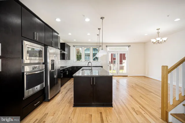 a kitchen with stainless steel appliances granite countertop a refrigerator a stove and a sink