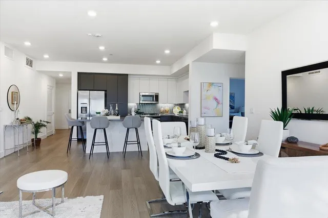 a living room with kitchen island furniture a large window and a clock