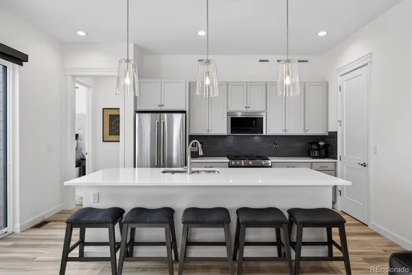 a kitchen with stainless steel appliances granite countertop a dining table chairs refrigerator and sink