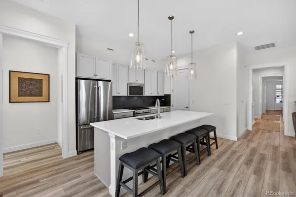 a kitchen with stainless steel appliances a table chairs refrigerator and wooden floor