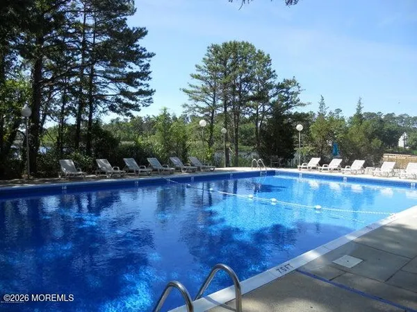 a view of a swimming pool with a bench and trees around