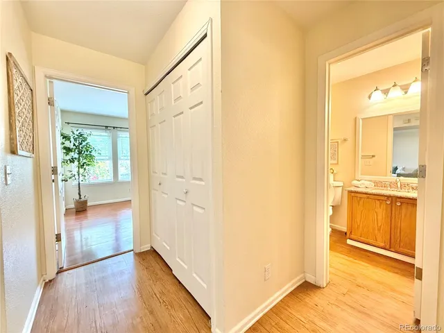 a view of a hallway with wooden floor and a bathroom