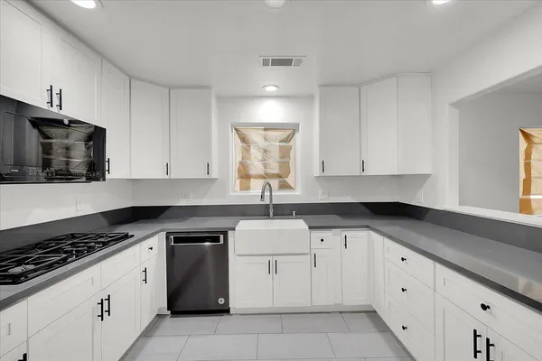 a kitchen with granite countertop white cabinets and stainless steel appliances