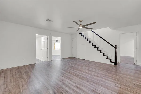 a view of an empty room with wooden floor and stairs