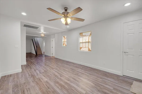 an empty room with wooden floor and windows