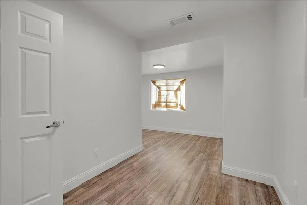 a view of an empty room with wooden floor and a window