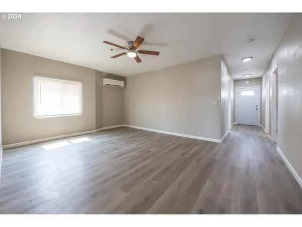 a view of an empty room with wooden floor and a window