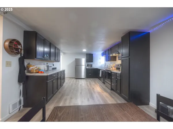 a open kitchen with a sink a refrigerator and wooden floor