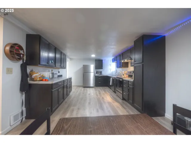 a open kitchen with a sink a refrigerator and wooden floor