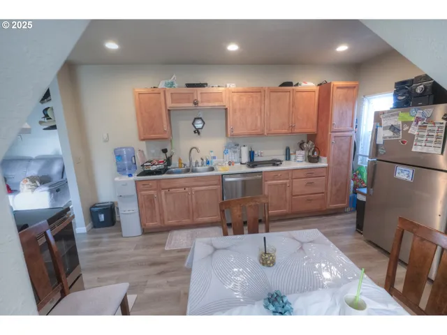 a living room with stainless steel appliances furniture a rug kitchen view and a faucet
