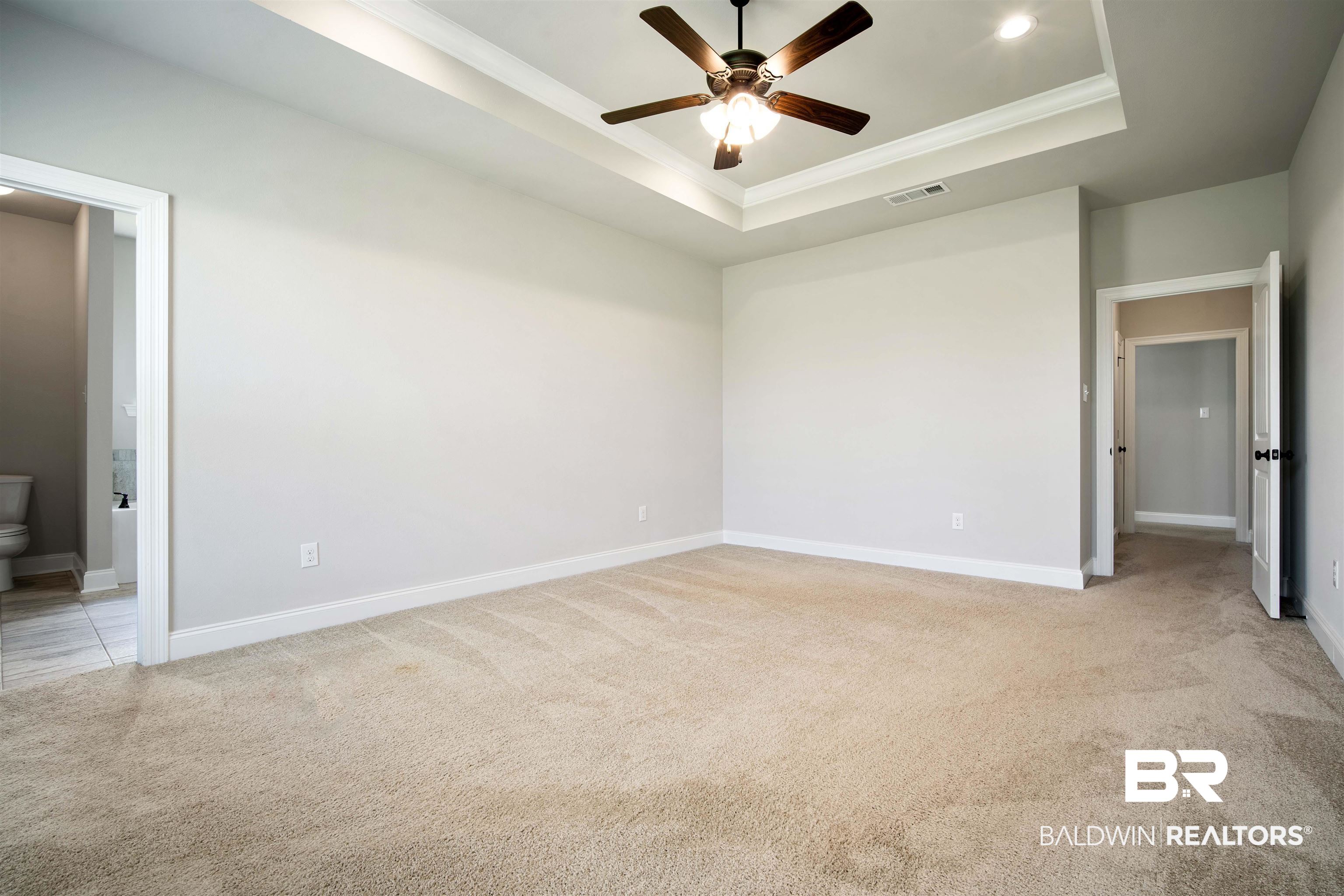 9924 Dunleith Loop Daphne, AL 36526 - Photo 15 of 33 Unfurnished bedroom featuring ornamental molding, a tray ceiling, visible vents, and light colored carpet