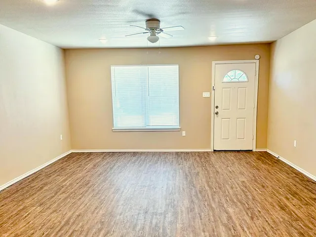an empty room with wooden floor closet and windows