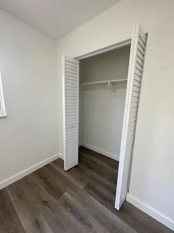 an empty room with wooden floor and closet