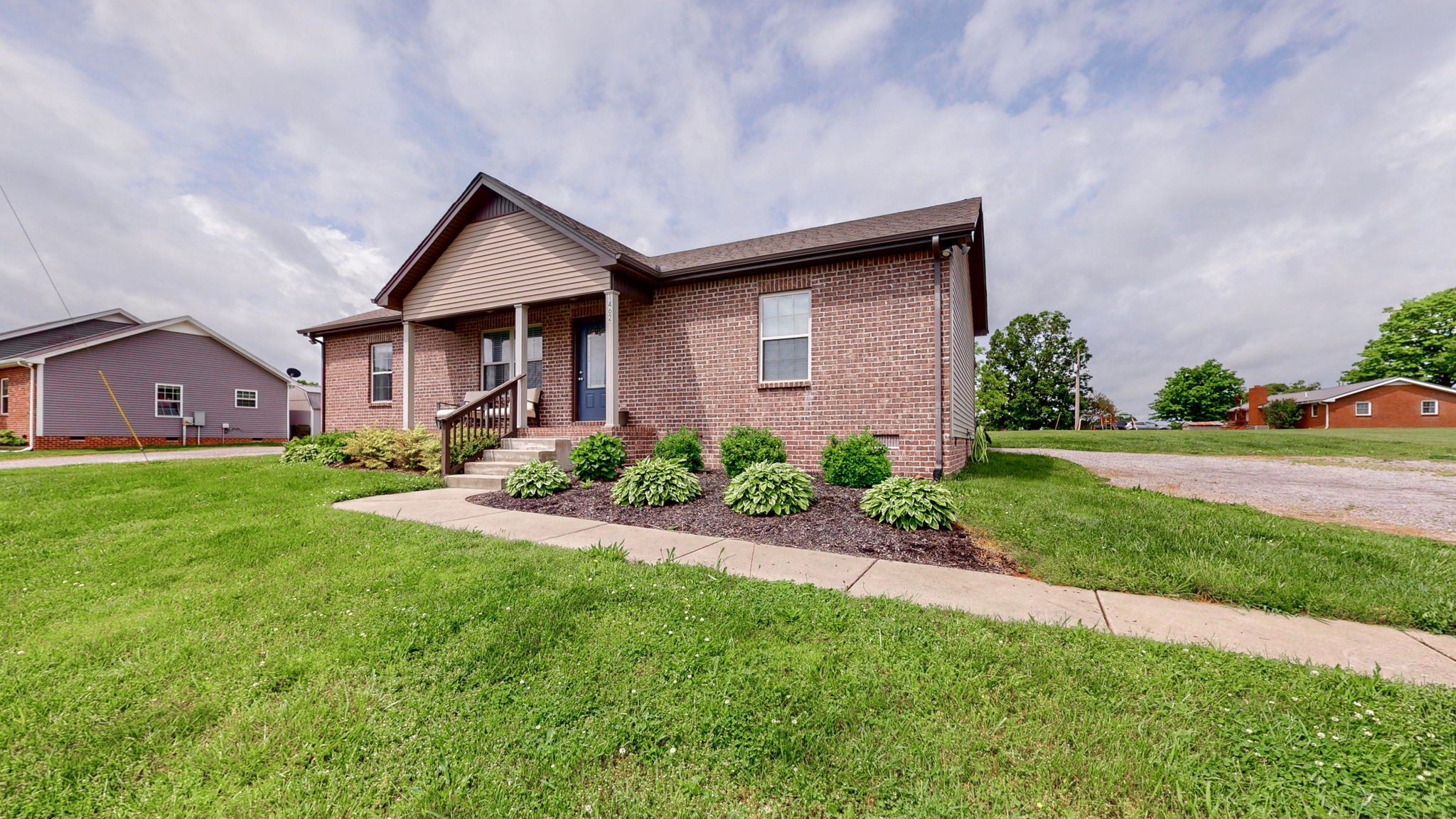 1462 East Ab Wade Road Portland, TN 37148 - Photo 36 of 52 a brick house with a small yard plants and big trees