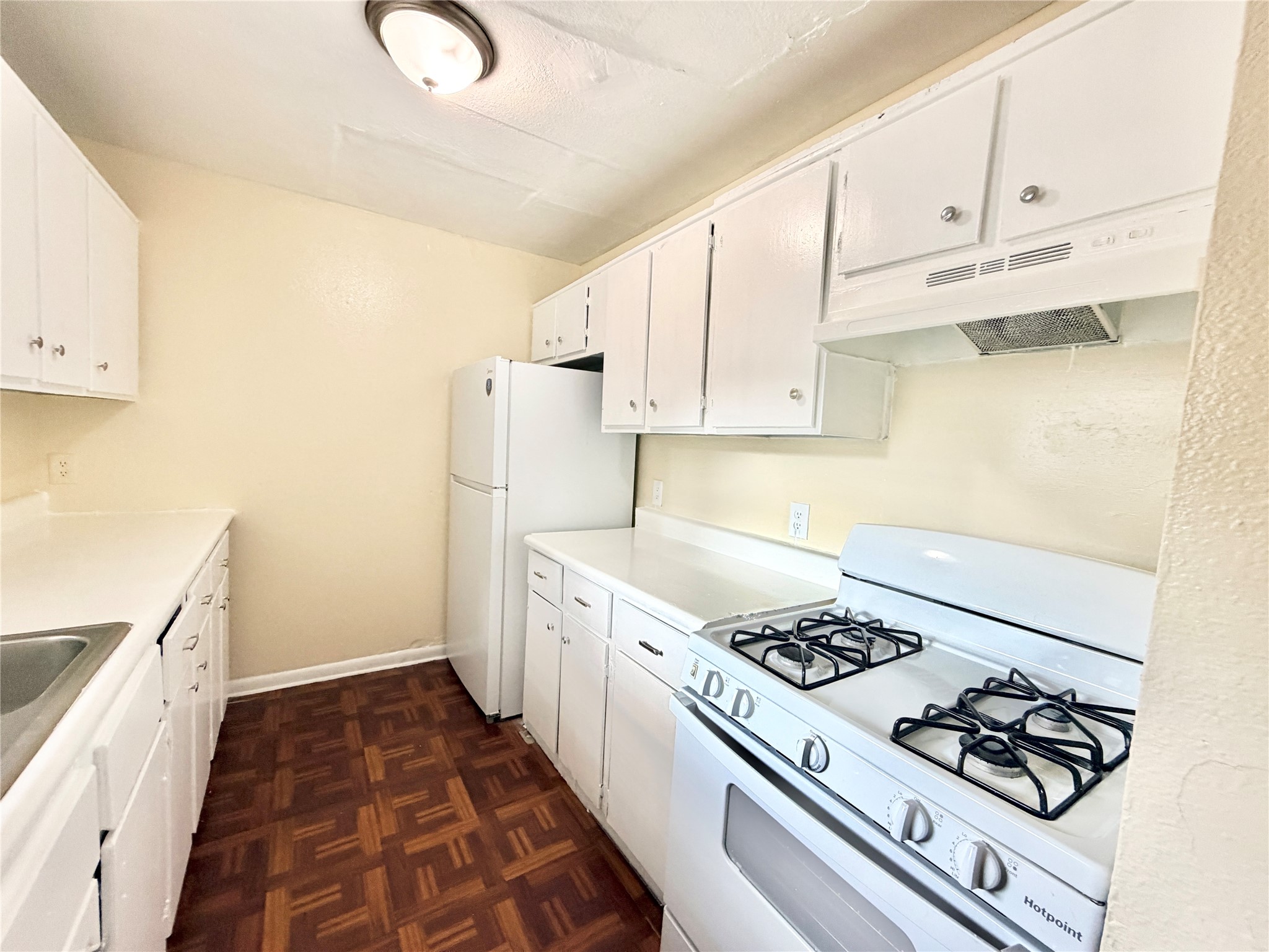 6257 Manor Road, Unit B Austin, TX 78723 - Photo 8 of 38 Efficient kitchen featuring ample white cabinetry, a built-in gas range, coordinating white appliances, durable countertops, and parquet-style flooring