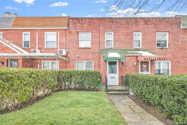 front view of a brick house with a yard