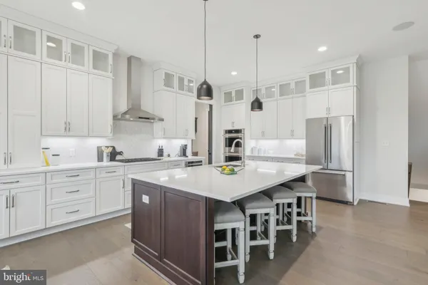a kitchen with stainless steel appliances kitchen island a table chairs sink and cabinets
