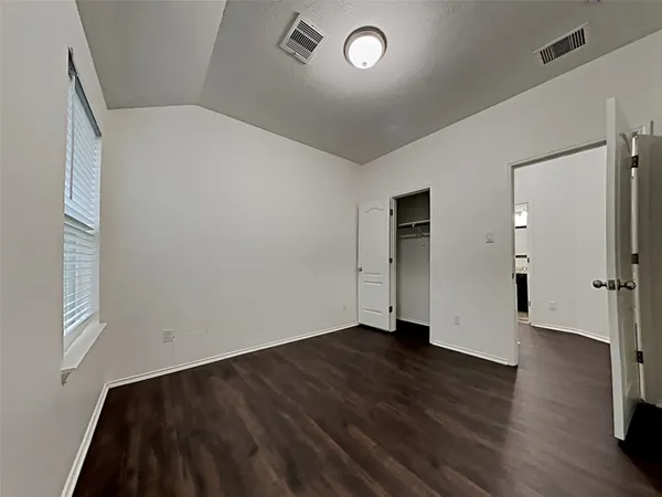 an empty room with wooden floor closet and windows