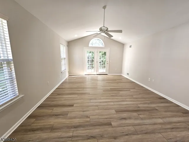 an empty room with wooden floor chandelier and windows