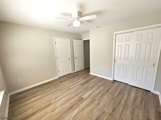 an empty room with wooden floor and ceiling fan