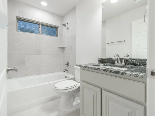 a bathroom with a granite countertop sink a toilet and bathtub