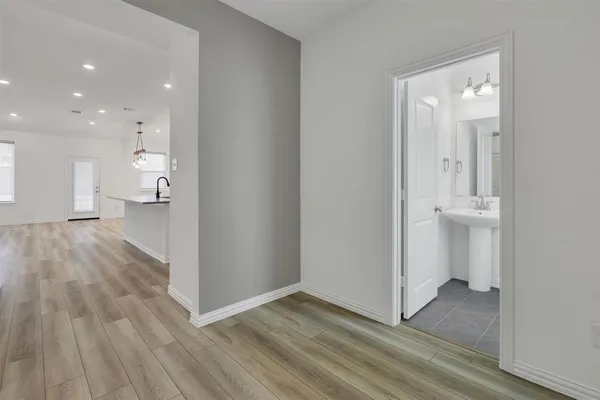 a view of a hallway with wooden floor and a bathroom