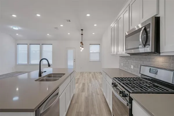 a kitchen with kitchen island granite countertop a sink stainless steel appliances and cabinets