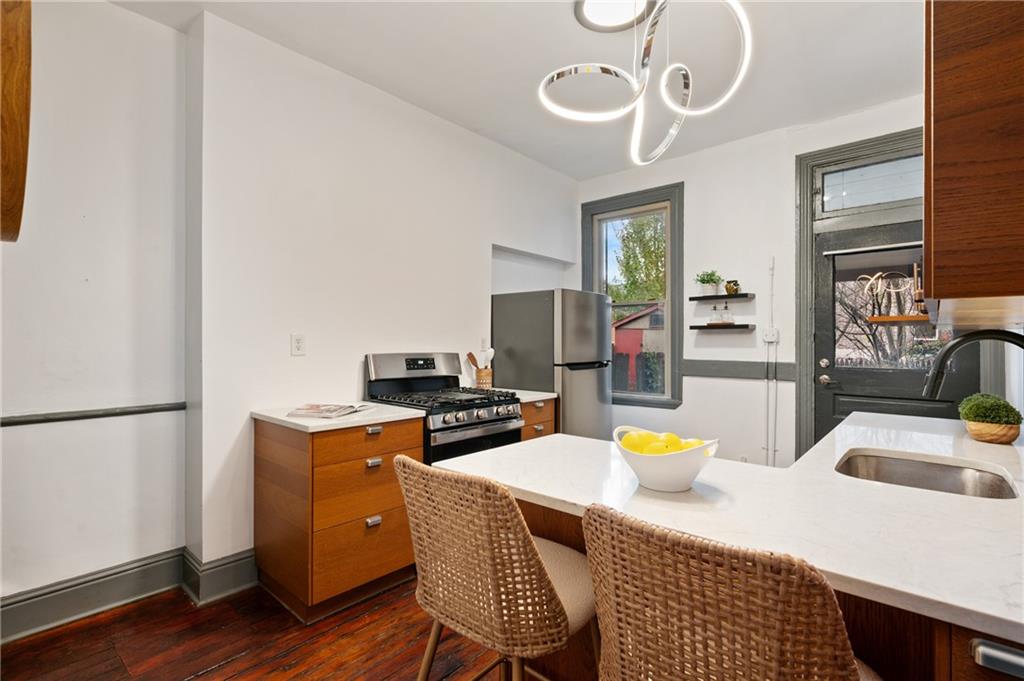 162 Almond Way Pittsburgh, PA 15201 - Photo 11 of 38 a kitchen with stainless steel appliances granite countertop a sink a stove a refrigerator a dining table and chairs with wooden floor