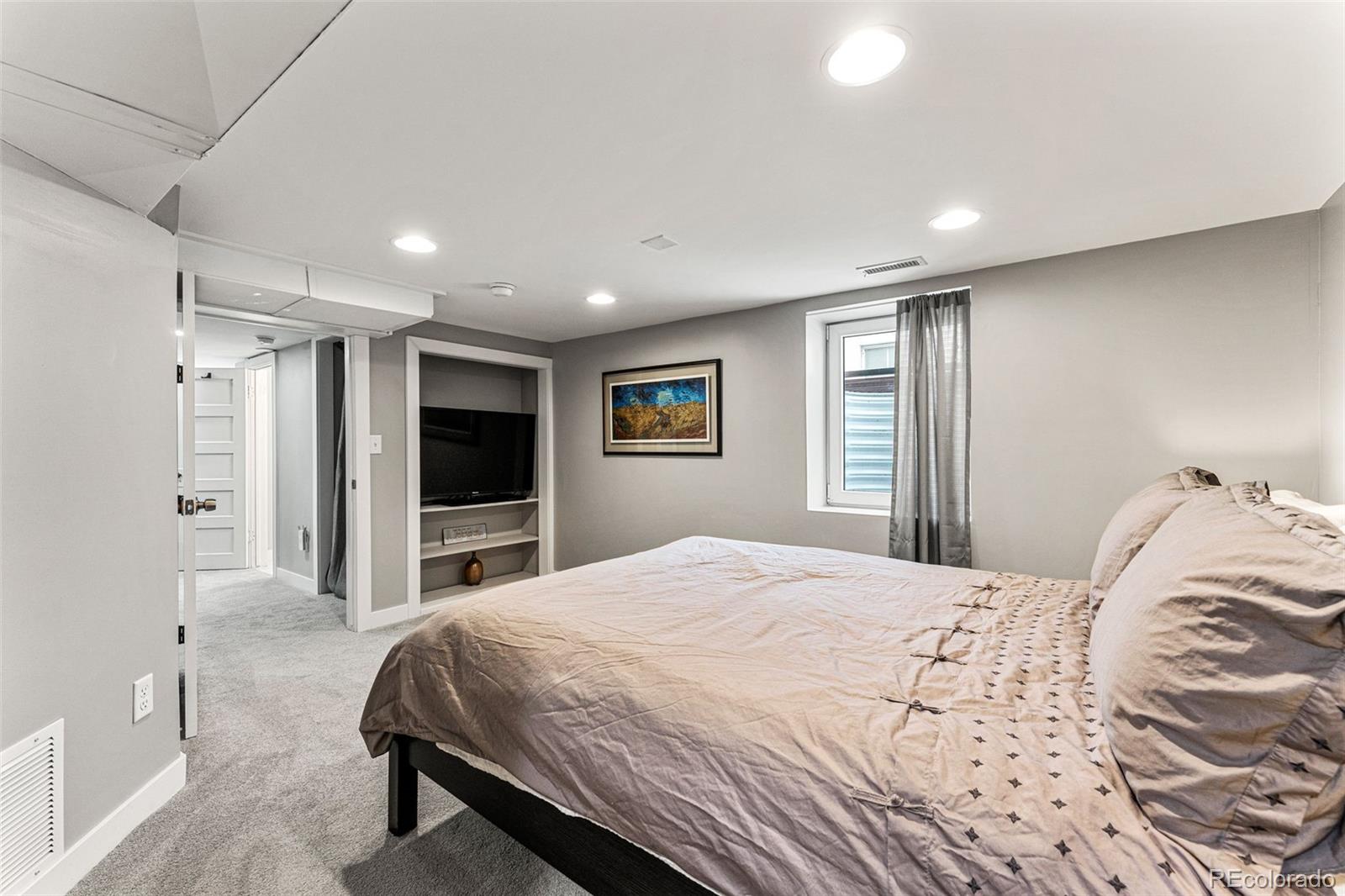 1639 Grape Street Denver, CO 80220 - Photo 26 of 39 a bedroom with a large bed and a flat screen tv