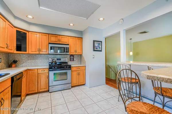 a kitchen with stainless steel appliances granite countertop a stove top oven a sink dishwasher a dining table and chairs with wooden floor