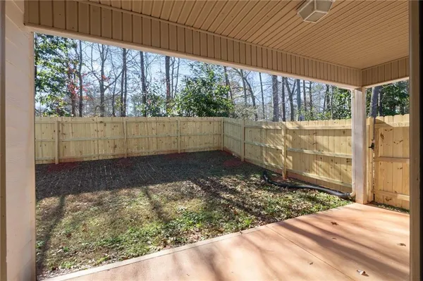 a view of a backyard with large trees and wooden fence