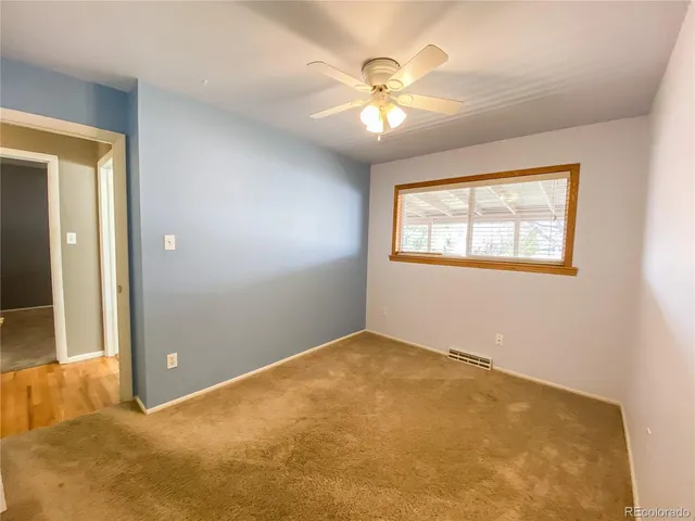 an empty room with windows and chandelier fan