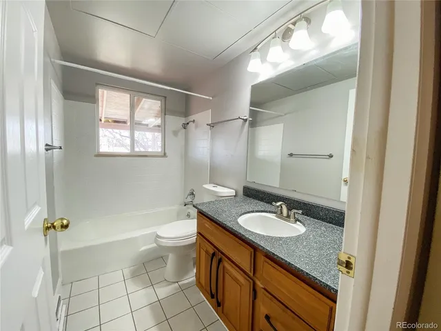 a bathroom with a granite countertop sink a toilet a mirror and shower