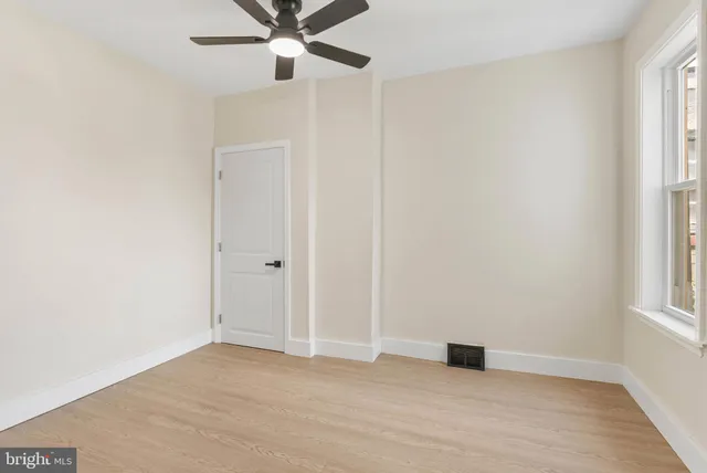 an empty room with windows and fan