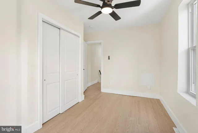a view of a room with wooden floor and a ceiling fan
