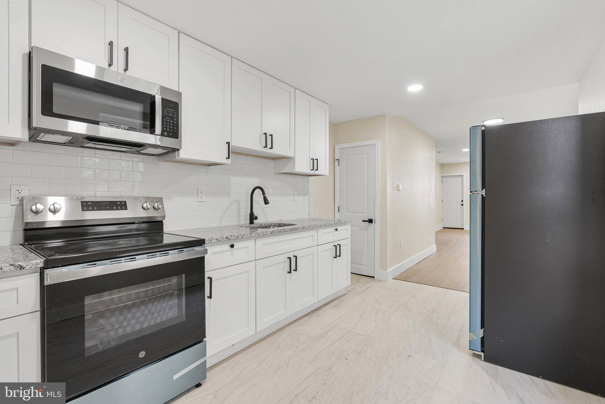 1221 North 50th Street Philadelphia, PA 19131 - Photo 9 of 24 a kitchen with stainless steel appliances granite countertop a stove microwave and refrigerator