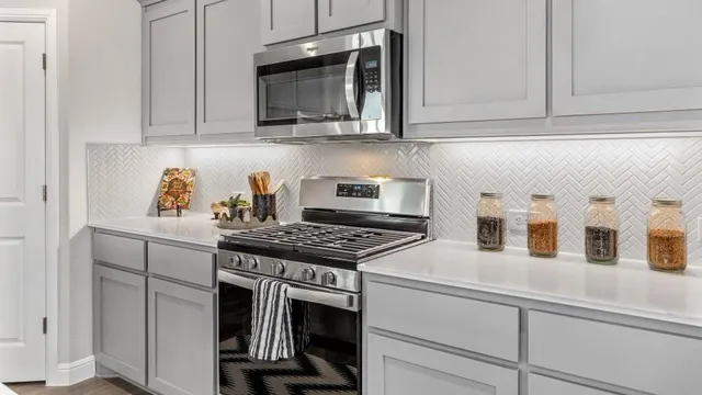 a kitchen with stainless steel appliances a sink a stove a refrigerator cabinets and chairs