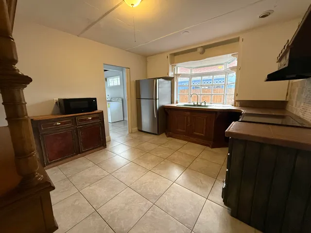 a kitchen with granite countertop a stove a sink and a refrigerator