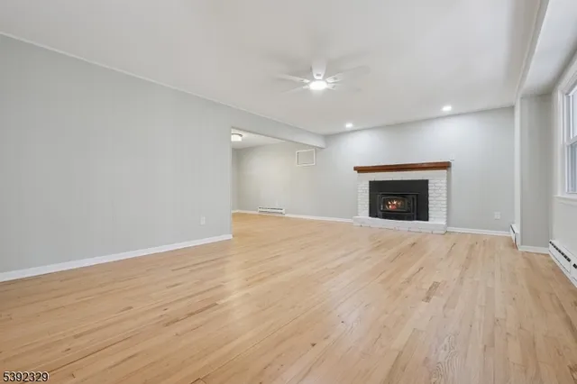 an empty room with wooden floor a fireplace and a window