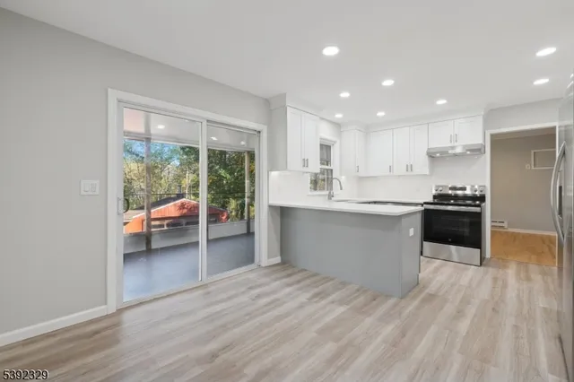 a large white kitchen with a large window a sink and stainless steel appliances